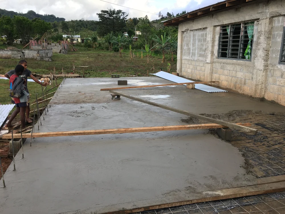 Completed concrete slab, local children looking on