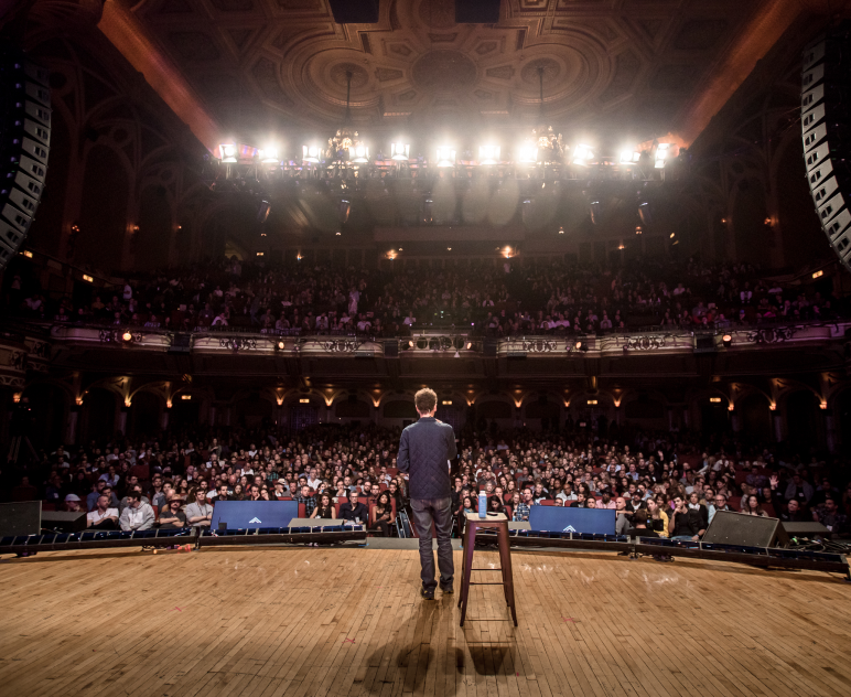 Speaker addressing a full theatre at a Summit event
