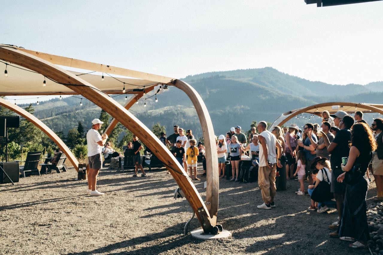 Outdoor gathering beneath timber arches, Summit Family Event